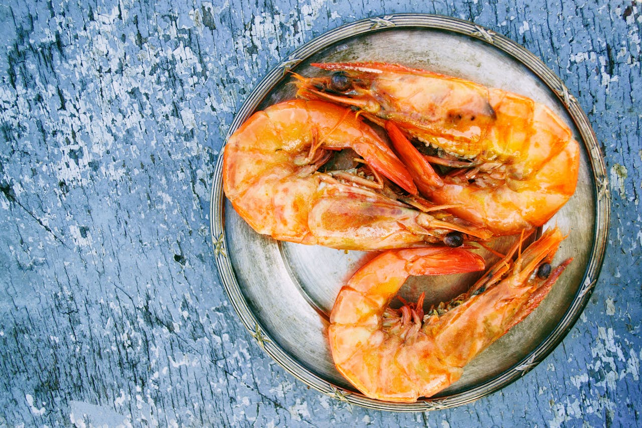 Top view of cooked shrimps on a metal plate on rustic surface. Perfect for seafood lovers.